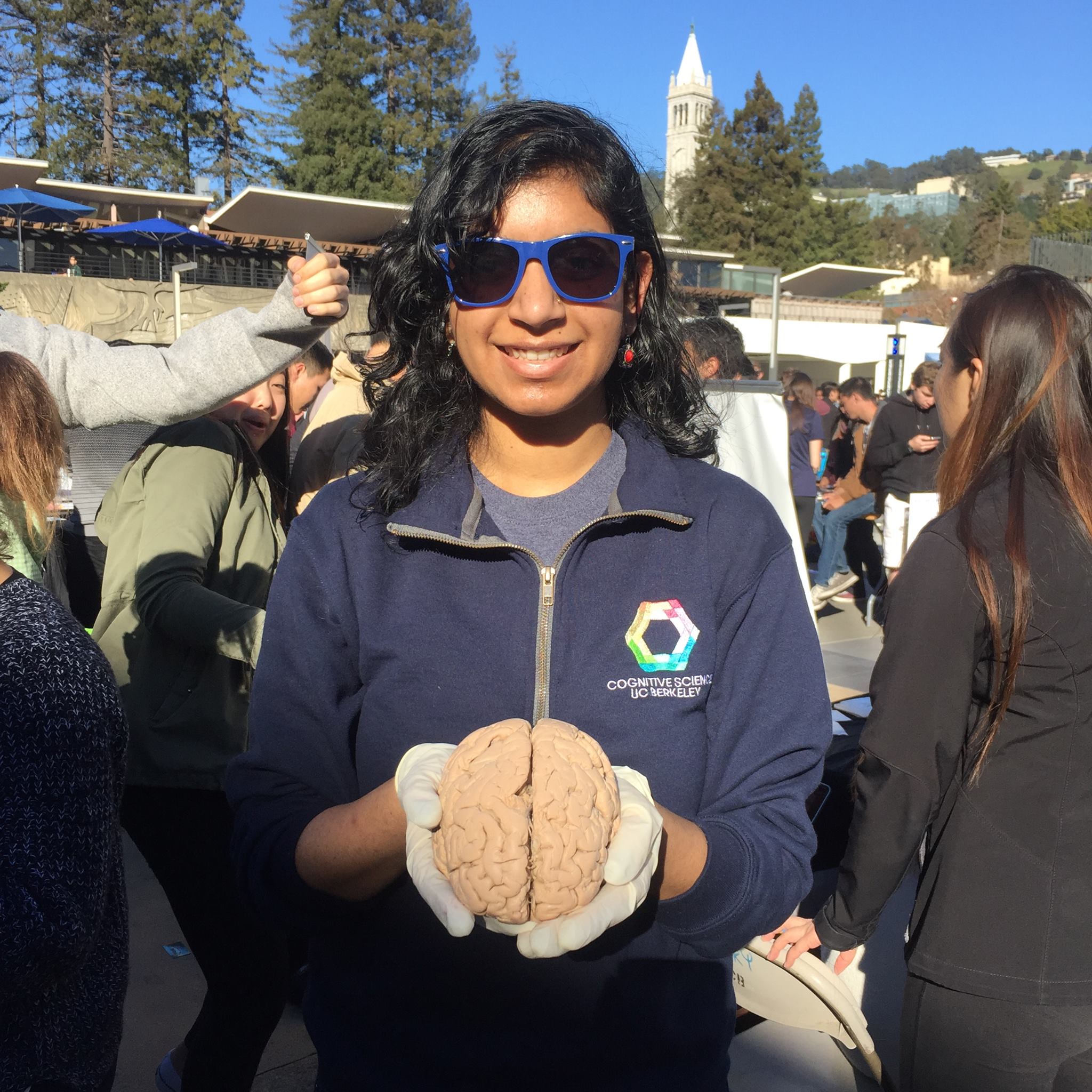 Harshali Wadge holding a model brain in front of UC Berkeley's Campanile